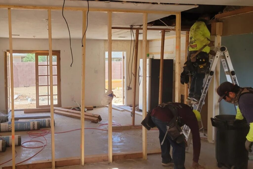 Home renovation in progress: contractors framing interior wall, exposed studs, ladder and tools during kitchen remodel.